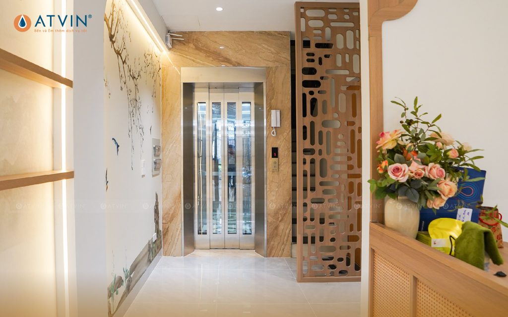 Thang máy mini với cửa tầng inox nhuyễn, khung bao bằng đá granite màu kem đồng bộ với màu sắc chủ đạo xung quanh.